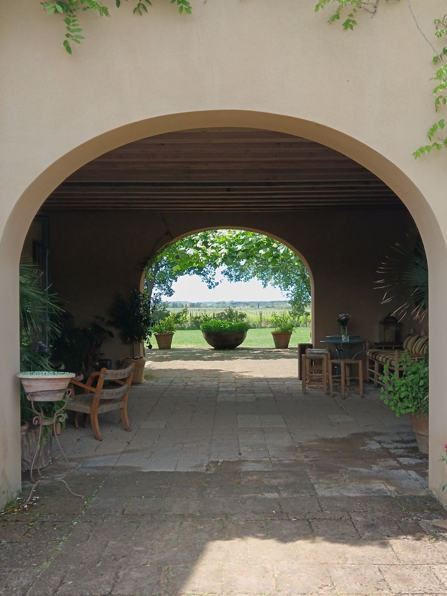 A winery courtyard in Bolgheri framing the vineyards through two arches