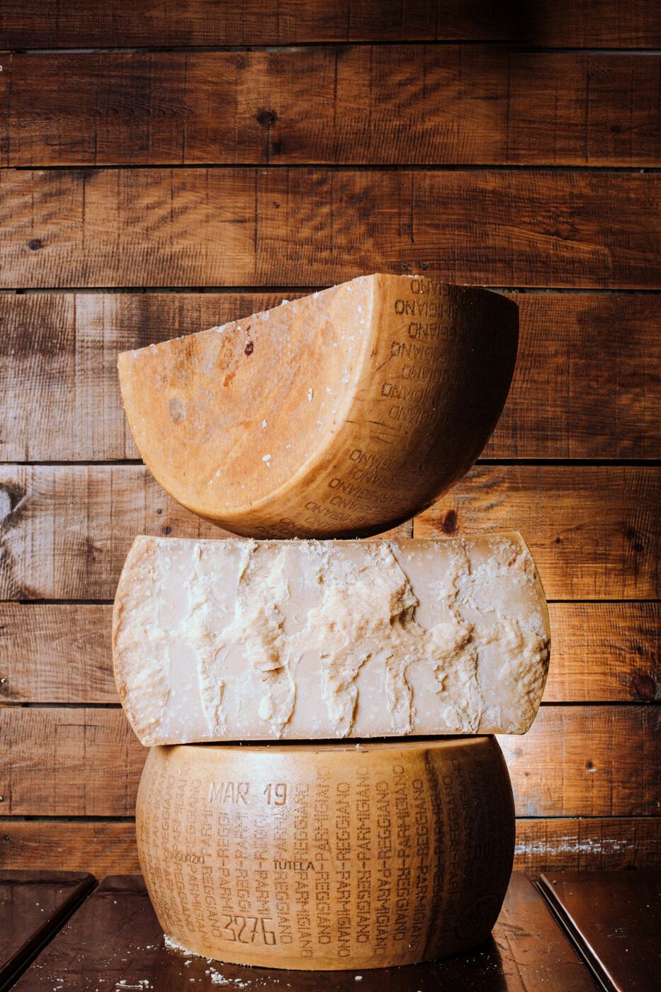 Aged wheels of Parmigiano Reggiano, one split to show the grain