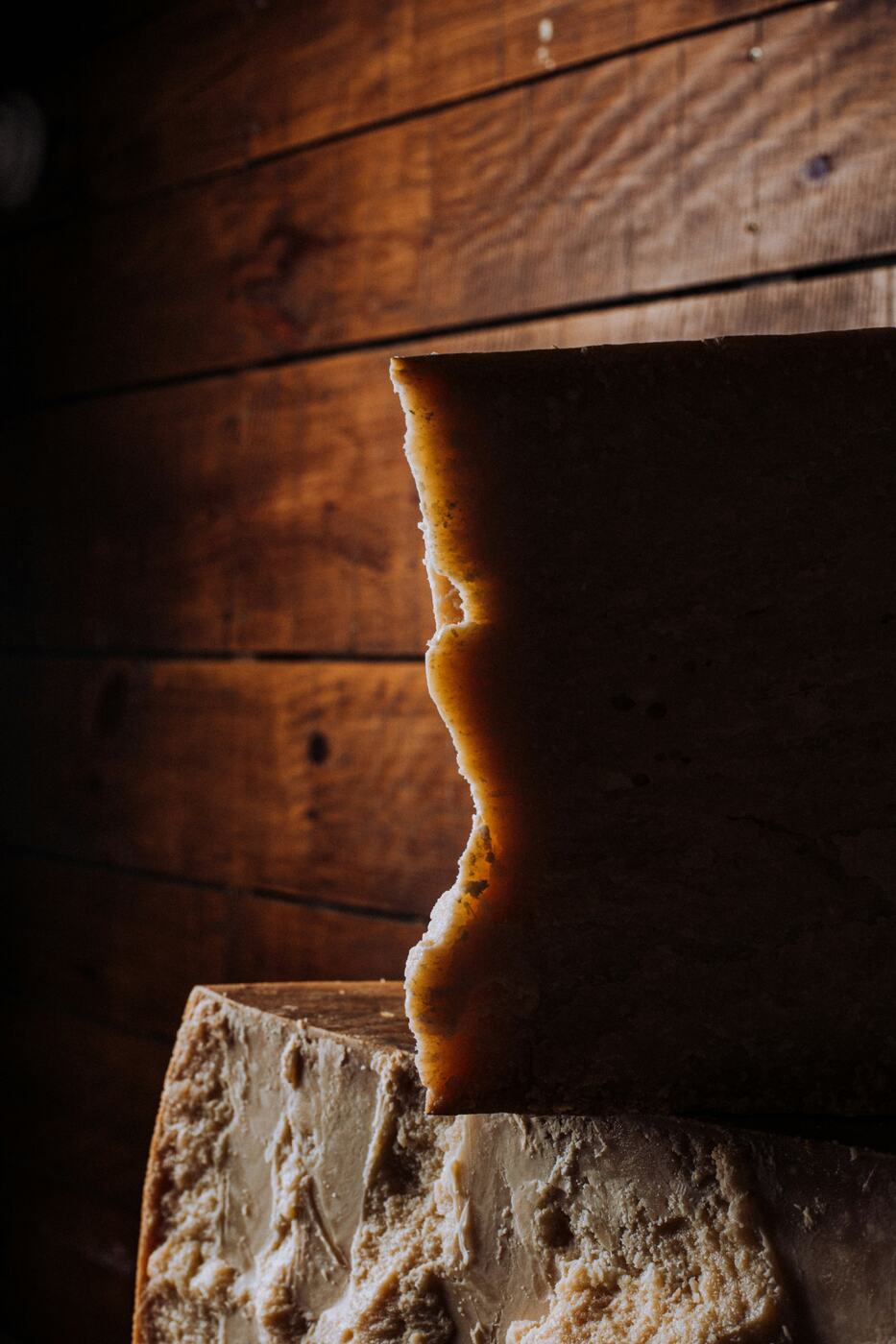 A wedge of aged Parmigiano Reggiano in warm light